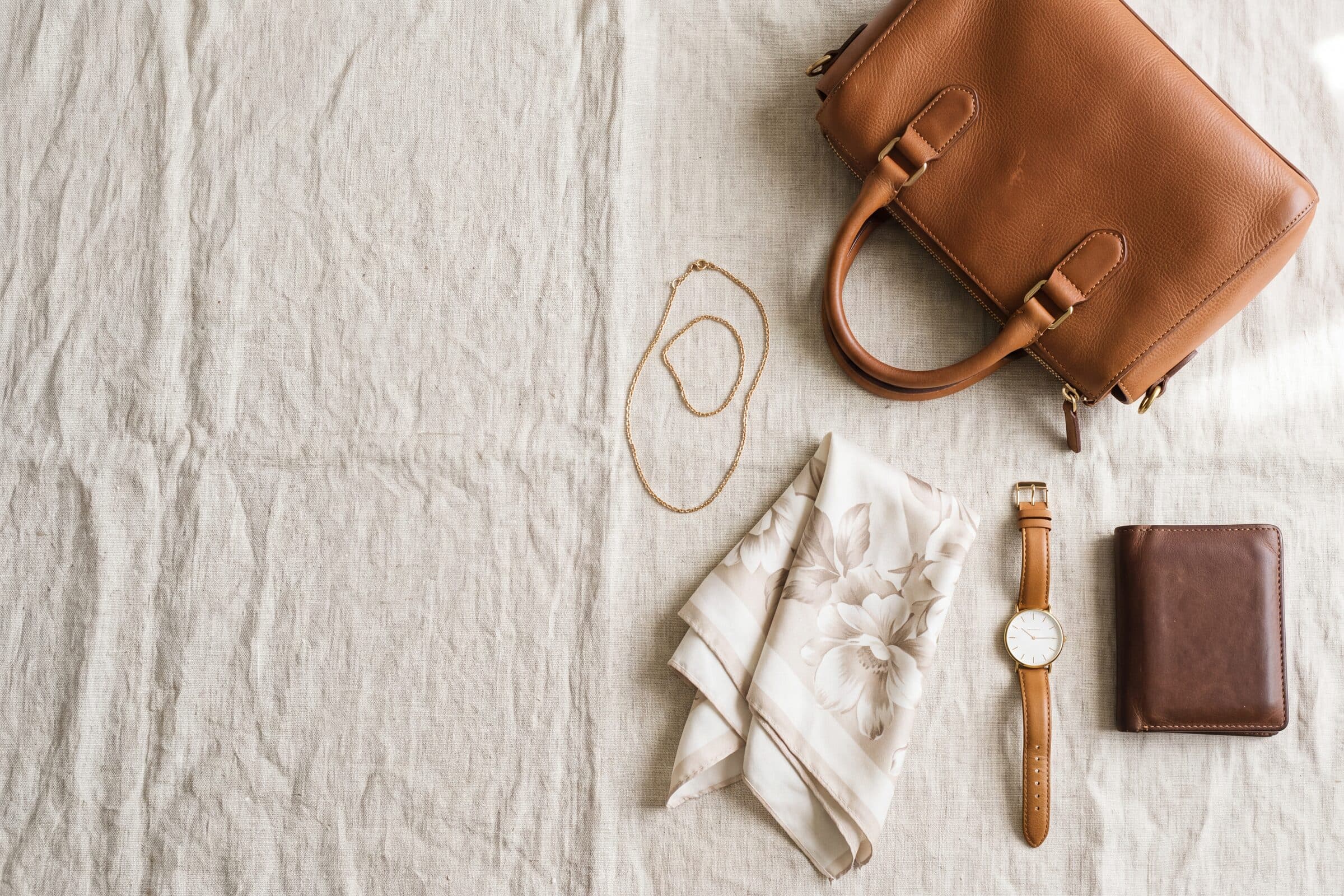 A group of pre-owned luxury pieces arranged on a warm neutral ground