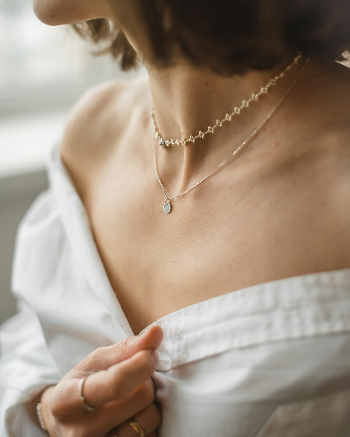 Gold station necklace photographed on a neutral ground