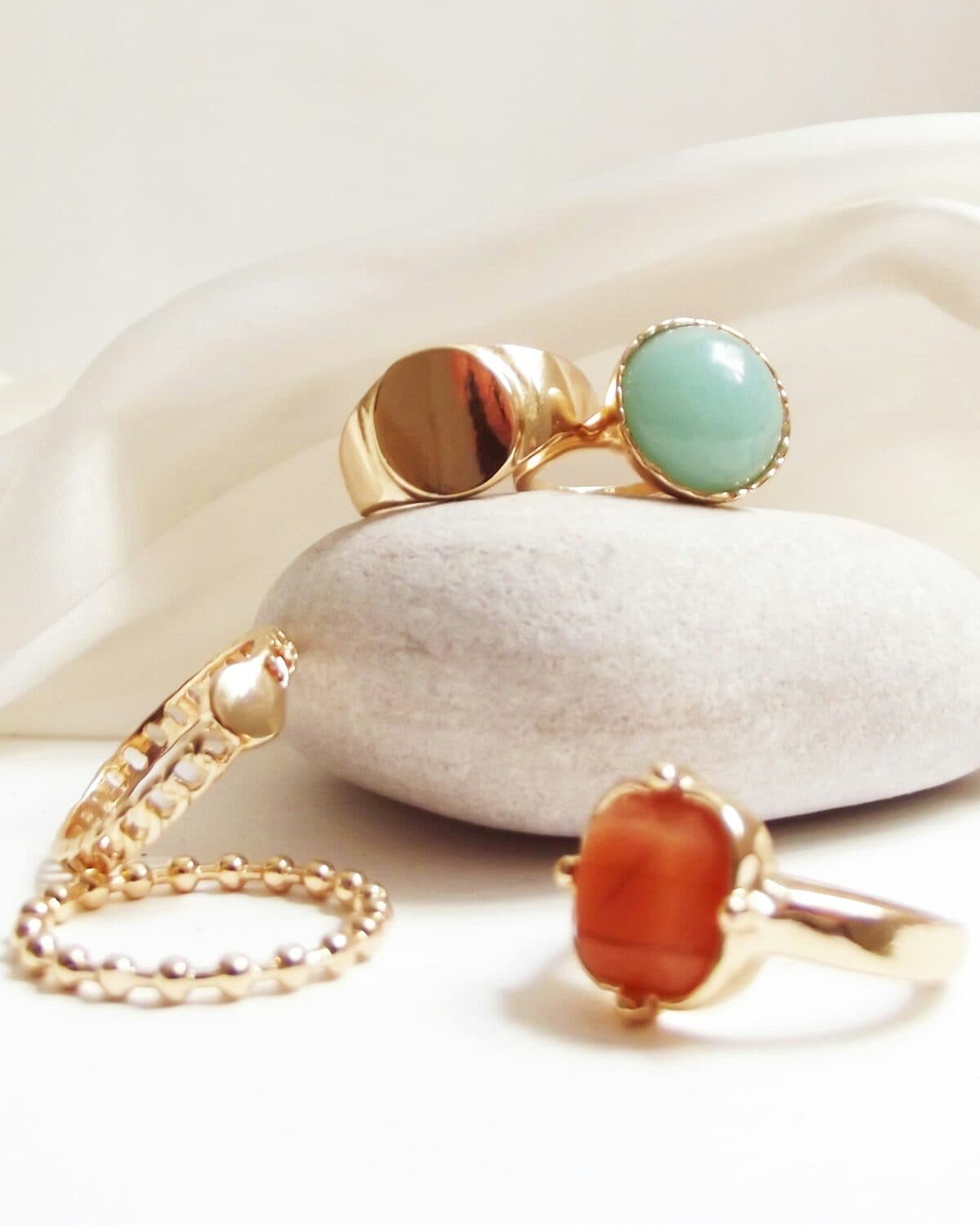Fine gold jewelry — necklaces and rings arranged on a cream ground
